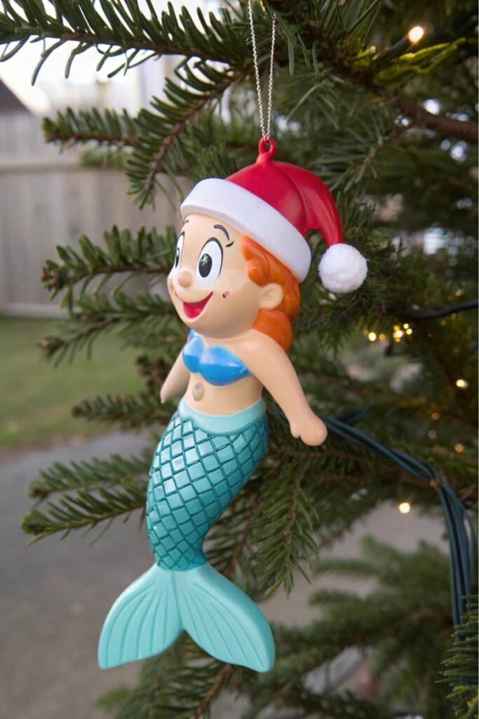 A mermaid wearing a Santa hat surrounded by 25 funny Christmas ornaments